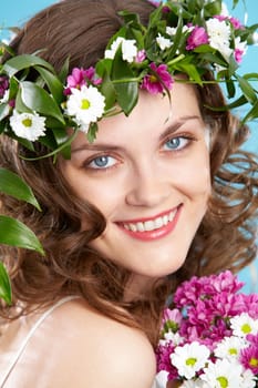 Beautiful woman in floral wreath looking at camera with smile