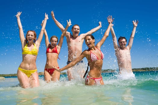 Image of happy teens playing in lake during their vacation