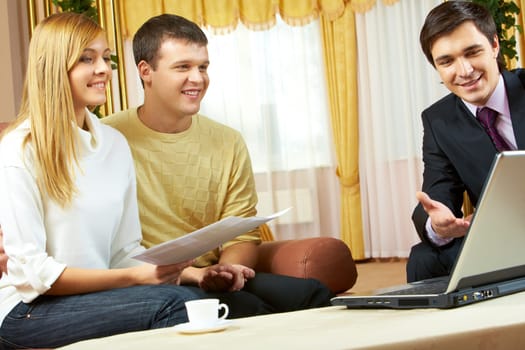 Portrait of a businessman explaining something in laptop to young couple