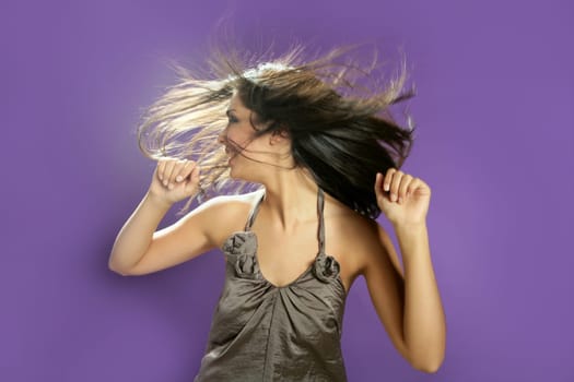 Brunette indian beautiful woman dancing at studio on purple background