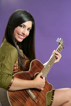Beautiful brunette playing acoustic guitar over purple background
