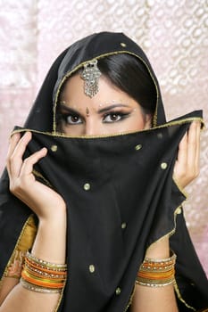 Beautiful brunette asian girl with black veil on face, traditional indian costume