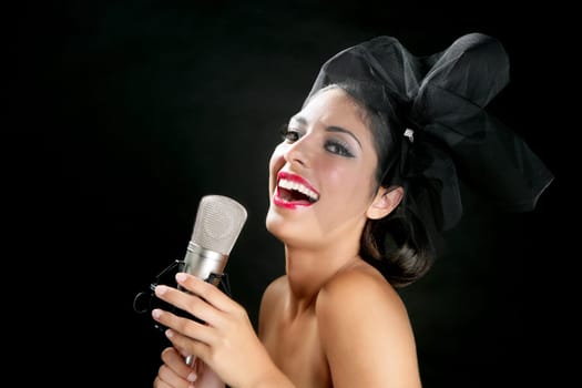 Beautiful woman singing on a vintage microphone on black background