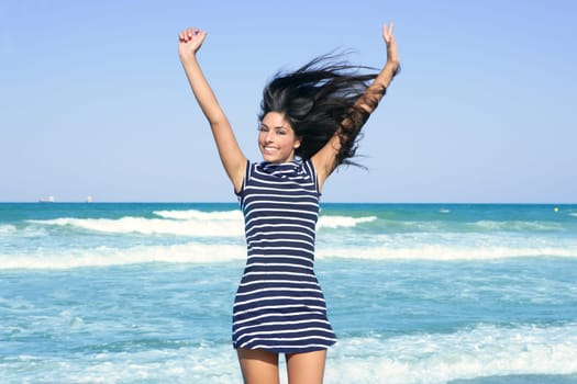 Beautiful summer brunette girl jumping on the blue beach