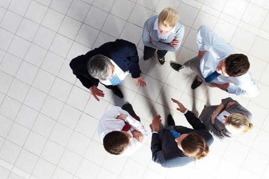Above angle of several smart associates talking to each other at meeting