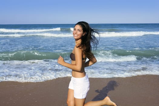 Beautiful summer brunette girl jumping on the blue beach