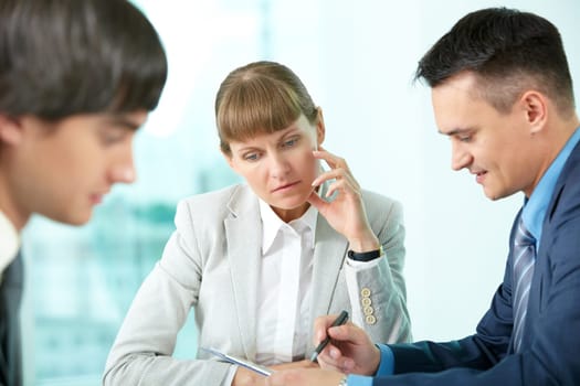 A businesswoman sitting in deep thought among her colleagues