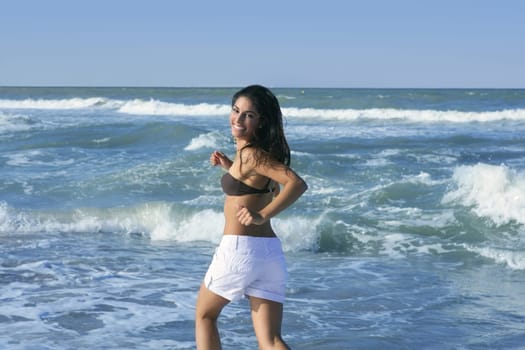 Beautiful summer indian brunette girl jumping on the blue beach