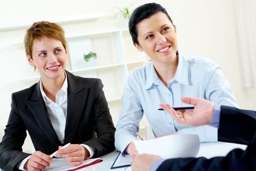 Portrait of two businesswomen looking at man during conversation