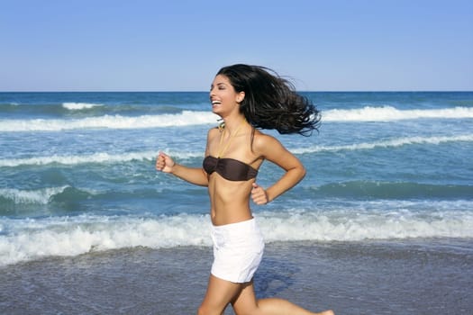 Beautiful summer indian brunette girl jumping on the blue beach