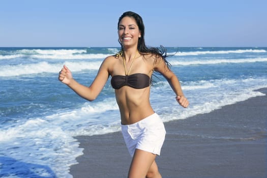 Beautiful summer brunette girl jumping on the blue beach