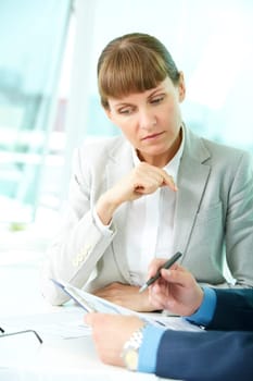 Portrait of confident woman looking at document while her partner explaining it