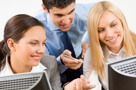 Successful businessman explaining something to his pretty colleagues while they looking at monitor