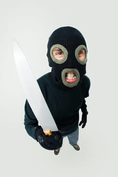 Fish-eye shot of gangster wearing black balaclava with knife in hand