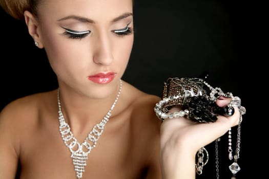 Ambition and greed in fashion woman with jewelry in hands on black background