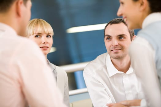 Friendly group of specialists speaking to each other at meeting