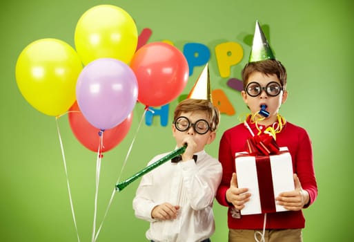 Portrait of smart boys in funny eyeglasses blowing into childish toys