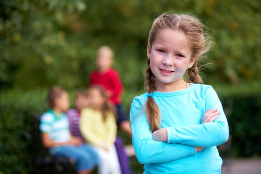 Portrait of happy girl crossing arms and looking at camera with her friends on background