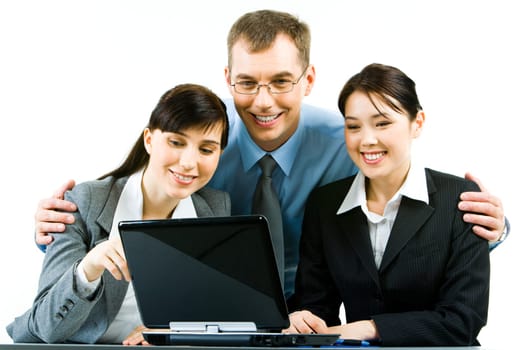 Portrait of smiling young woman sitting at the table with their leader standing behind them and looking at laptop screen together