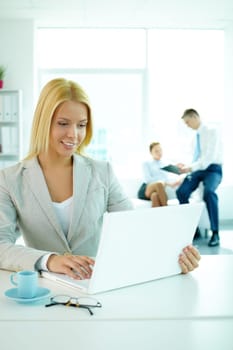 Portrait of pretty secretary looking at laptop screen in working environment