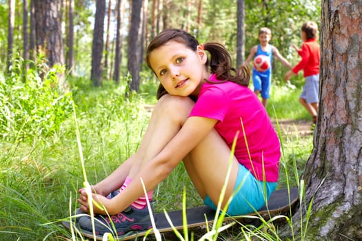 Portrait of a young girl sitting on ground in wood