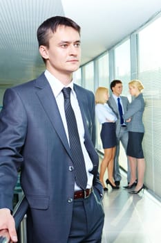 Portrait of a young confident businessman with working team on background
