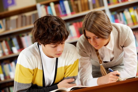 Portrait of clever students reading book in college library