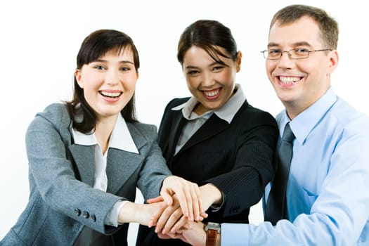 Portrait of three business partners making pile of their hands and looking at camera with smiles