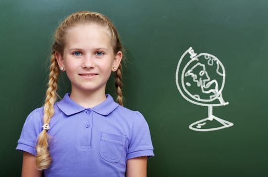 Portrait of smart girl by the blackboard looking at camera