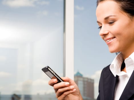 Image of pretty woman holding her mobile and sending sms