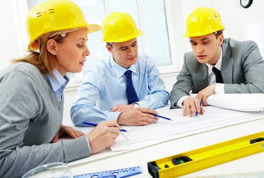 Three architects sitting at table and discussing paperwork