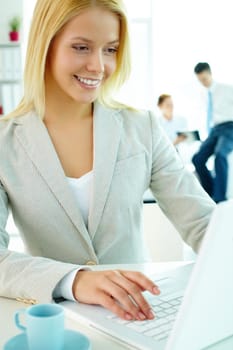 Portrait of pretty secretary looking at laptop screen in working environment