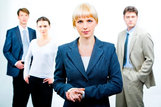 Portrait of serious businesswoman wearing suit on the background of three confident businesspeople