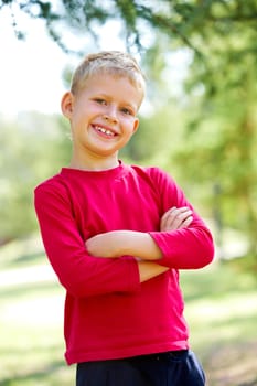 Portrait of happy lad crossing arms and looking at camera with smile