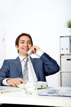 Portrait of happy businessman talking on phone in office