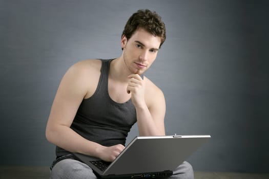 handsome student young man sit working on laptop over gray background
