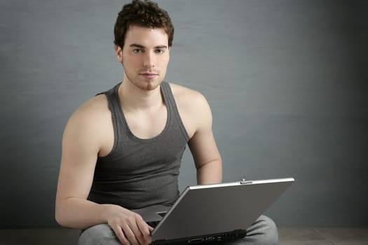 handsome student young man sit working on laptop over gray background