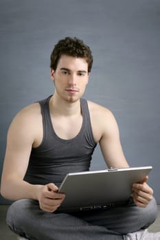 handsome student young man sit working on laptop over gray background