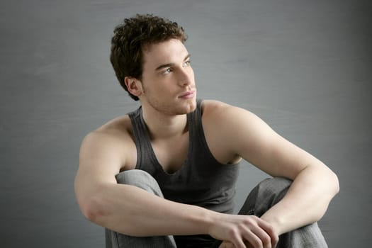 casual young man portrait sit over gray grunge background