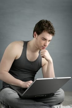 handsome student young man sit working on laptop over gray background