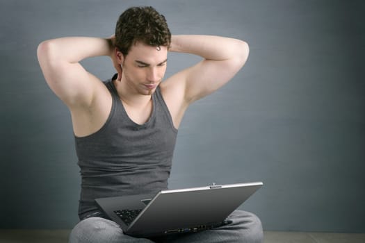 handsome student young man sit working on laptop over gray background