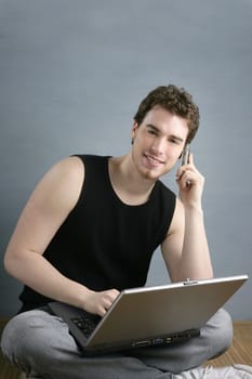 casual student talking mobile phone laptop sit over gray grunge background