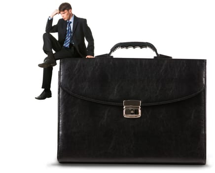 Image of thoughtful businessman sitting on briefcase