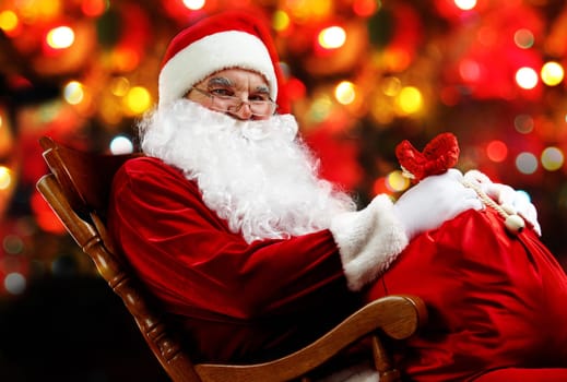 Santa sitting with a sack against sparkling lights