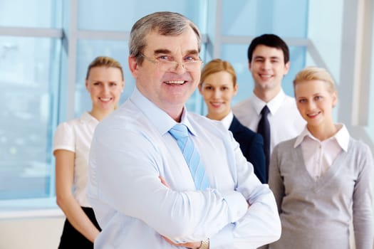 Image of senior leader smiling at camera with several employees behind