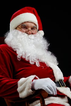 Santa sitting and smiling isolated on black