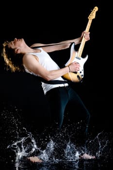 Portrait of young modern guitarist playing instrument while walking in water