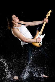 Portrait of young performer playing electrical guitar in water splashes