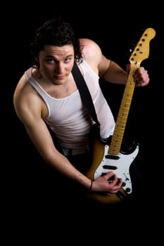 Portrait of guitar player in vest holding instrument over black background