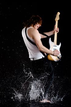 Portrait of young performer playing electrical guitar in water splashes and singing